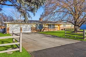 Einbungalow mit Garage, Vorgarten und einem großen Baum.