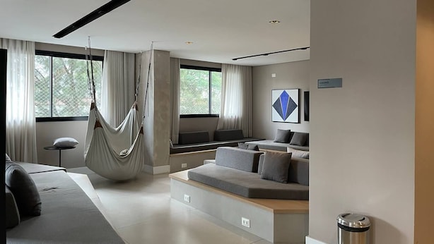 A modern living room with a hammock, a sofa, and a dining area. - Today Pinheiros NR (Sao Paulo)
