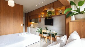 A modern hotel room with a bed, a dining table with chairs, a TV, and a potted plant. - Today Pinheiros NR (Sao Paulo)