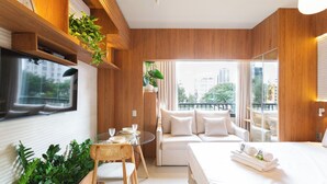 A modern hotel room with a large bed, a sofa, a dining area with a table and chairs, and a balcony with a view of the city. - Today Pinheiros NR (Sao Paulo)