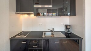 Een moderne keuken met een zwart aanrecht, een roestvrijstalen spoelbak en een koffiezetapparaat.