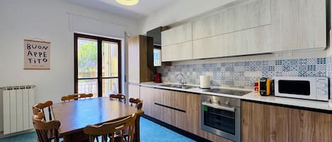 Una cocina moderna con armarios de madera, una mesa de comedor con sillas, microondas y cafetera.