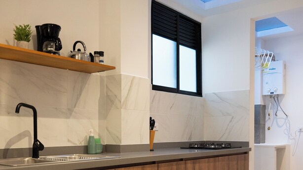 A modern kitchen with a built-in sink, wooden cabinets, and a window above the countertop. - Deluxe queen suite (Salento)
