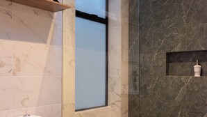 Une salle de bain moderne avec des toilettes, une douche en verre et un mur recouvert de carreaux de marbre.