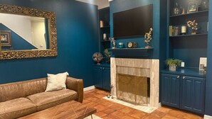 Un salon avec un canapé en cuir marron, une table basse en bois, une cheminée et un mur d’accent bleu.