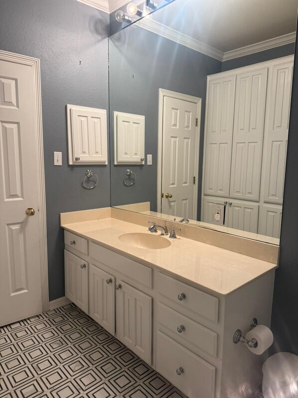 A bathroom with a double sink vanity, a large mirror, and a patterned floor.