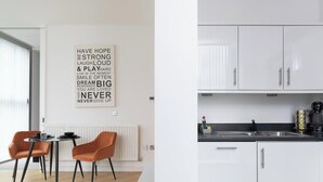 Una cocina moderna con armarios blancos, encimera negra y una cafetera.