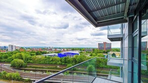 A modern building with large windows and a view of a railway system and greenery. - Waterfront 2BR | 2 Bath | Free Gym + Parking (Manchester)