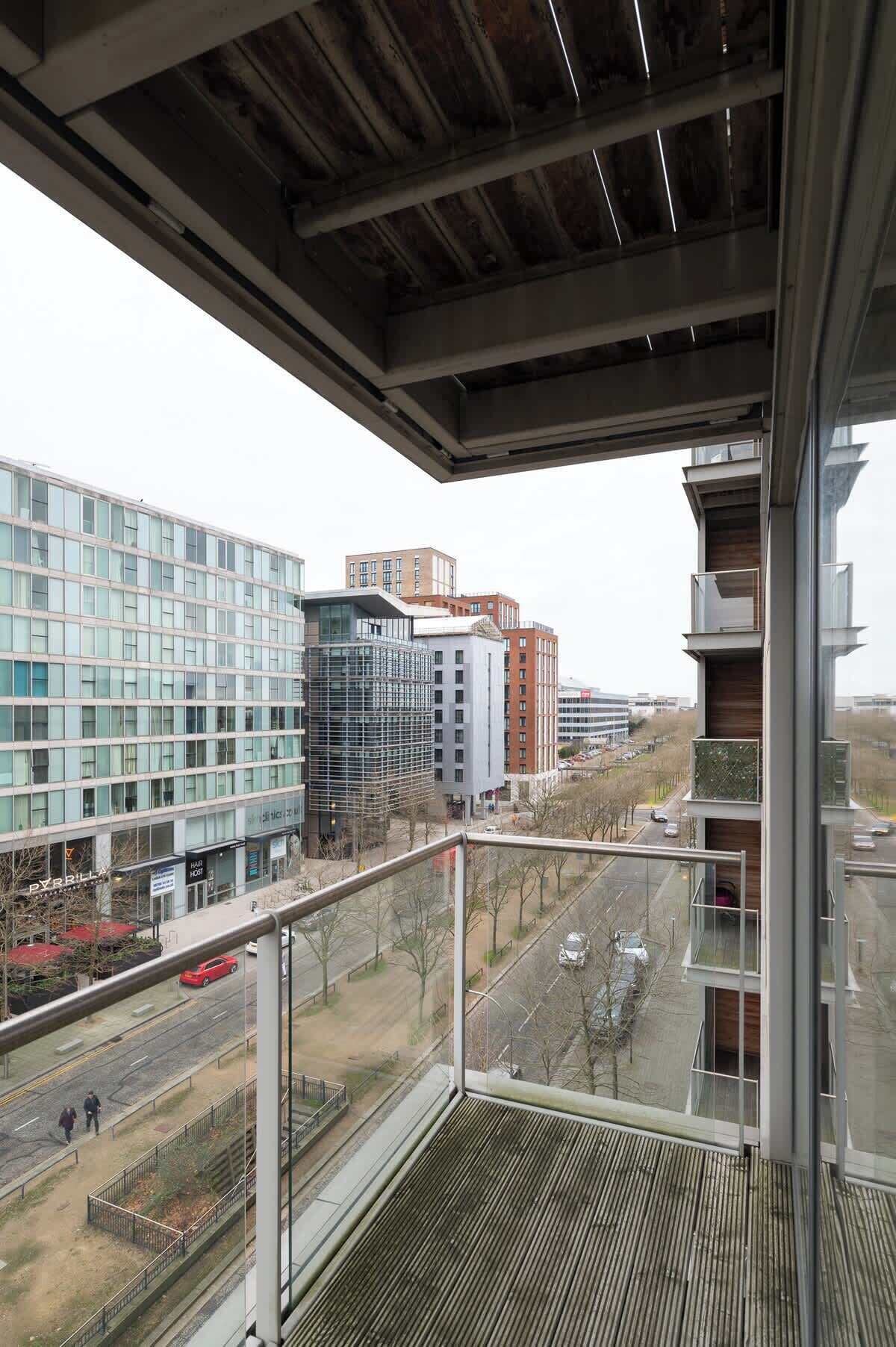 A high-rise building with a modern architectural design, featuring large windows and a metal balcony railing.