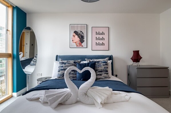 A bedroom with a bed, a mirror, a dresser, and wall art.