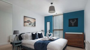 Una camera da letto con un letto, un comodino, una lampada, una cassettiera e opere d'arte alle pareti.