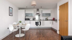 Una cucina moderna con mobili bianchi, un tavolo da pranzo con sedie e una porta in legno.