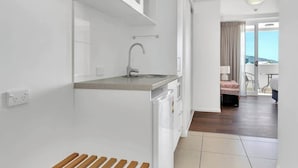 A modern kitchen with a built-in sink, a dining area with a table and chairs, and a view of the outdoors. - Coastal Chic in Heart of Cairns with Rooftop Pool (Cairns)