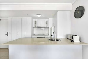 Una cucina moderna con mobili bianchi, un'isola centrale con lavello e un tostapane sul piano di lavoro.