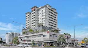 Un hotel de varios pisos con balcones, un restaurante en la planta baja y un área de estacionamiento.