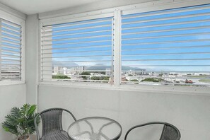 Varanda com vista para a cidade, um vaso de planta e duas cadeiras de vime.