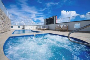 A rooftop pool area with two hot tubs, lounge chairs, and a view of the sky. - Seaside Azul—A Central Studio with Rooftop Pool (Cairns)