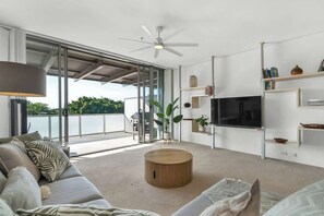 Un soggiorno moderno con una grande TV, una ventola a soffitto e vista sull'esterno.