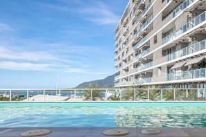 Un albergo con piscina, vista mare e montagne sullo sfondo.