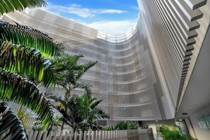 A modern building with a curved facade, a series of vertical lines, and a palm tree in the foreground.