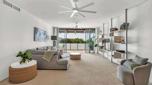 A modern living room with a sofa, armchair, round coffee table, and a ceiling fan.