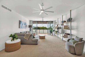 Un soggiorno moderno con divano, poltrona, tavolino rotondo e ventilatore a soffitto.