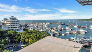 A marina with numerous boats docked, a building with a modern design, and a clear blue sky.