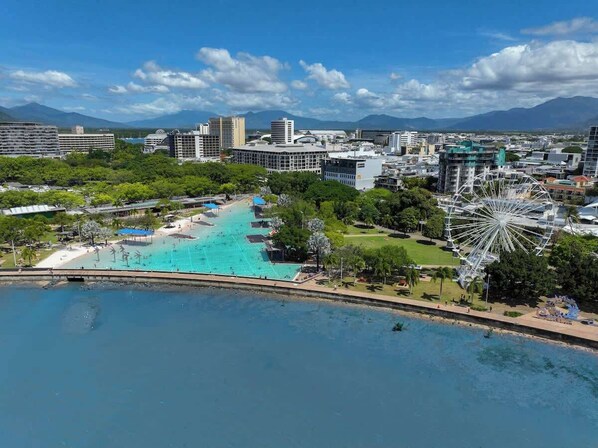 Un paysage urbain côtier avec une grande piscine publique, une grande roue et des bâtiments modernes.