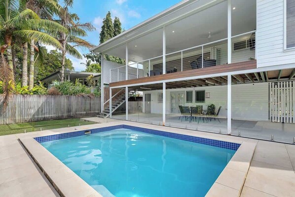 Une maison moderne à deux étages, dotée d’une piscine, d’un patio couvert et offrant une vue sur le jardin arrière.