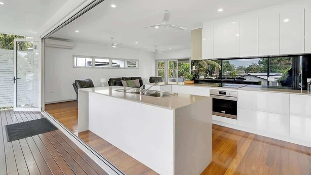 A modern kitchen with a central island, built-in appliances, and large windows.
