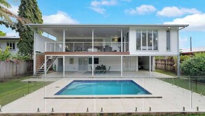 A modern two-story house with a swimming pool, a covered patio, and a staircase leading to the upper level.