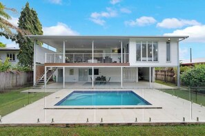 Una moderna casa a due piani con piscina, un portico coperto e una scala che conduce al piano superiore.