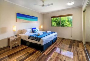 Una camera da letto con un letto, comodini, una ventola a soffitto, una finestra vista e un quadro appeso al muro.