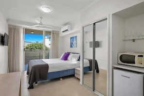Una camera da letto con un letto, un comodino, un forno a microonde e una porta-finestra che dà su un balcone.