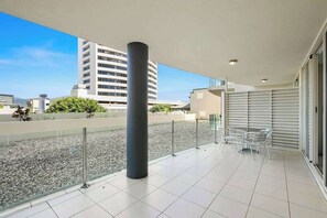 A balcony with a tiled floor, a metal railing, and a glass door leading to an indoor area. - Resort-Style Cityview Getaway in Perfect Location (Cairns)
