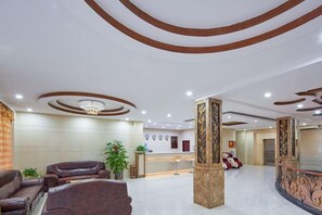 Un hall d’hôtel comprenant un comptoir d’accueil, un espace salon et un plafond décoratif.