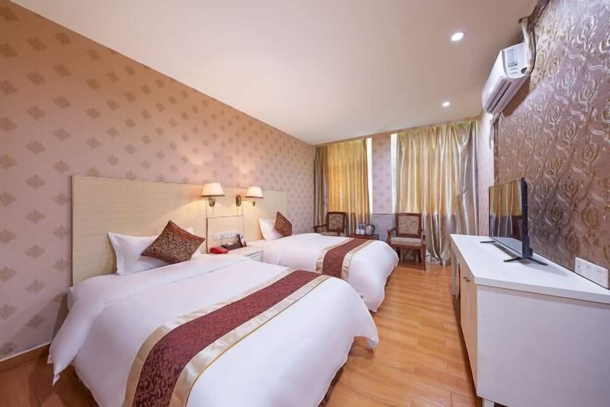 Ein Hotelzimmer mit zwei Betten, einem Schreibtisch, einem Stuhl und einer Klimaanlage.