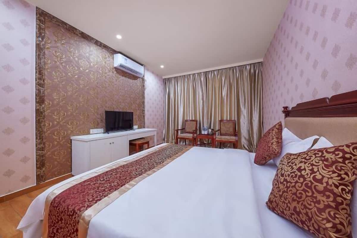 Ein Hotelzimmer mit Bett, Schreibtisch, Fernseher und einem Fenster mit Vorhängen.