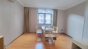 A room with a wooden floor, a dining table with chairs, a window with curtains, and a bed. - Guangzhou Jintai Hotel (Jianggao Store) (Guangzhou)