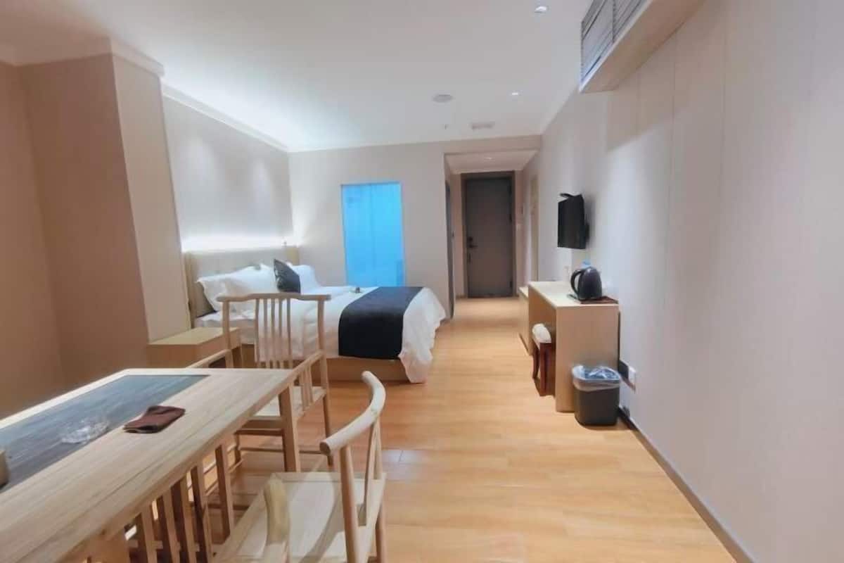 Ein Hotelzimmer mit einem Bett, einem Schreibtisch, Stühlen, einem Fernseher und einem Mülleimer.