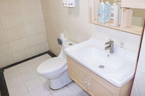 A bathroom with a toilet, sink, and a shelf with toiletries. - Guangzhou Jintai Hotel (Jianggao Store) (Guangzhou)