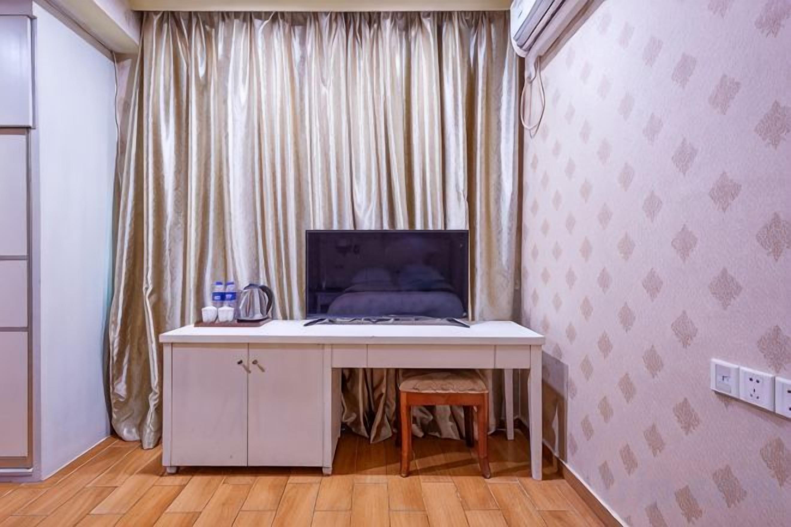 A room with a desk, chair, and a bed with a headboard.