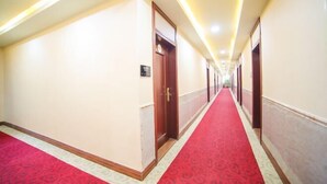 A hotel corridor with a red carpet, wooden doors, and a light-colored wall. - Guangzhou Jintai Hotel (Jianggao Store) (Guangzhou)