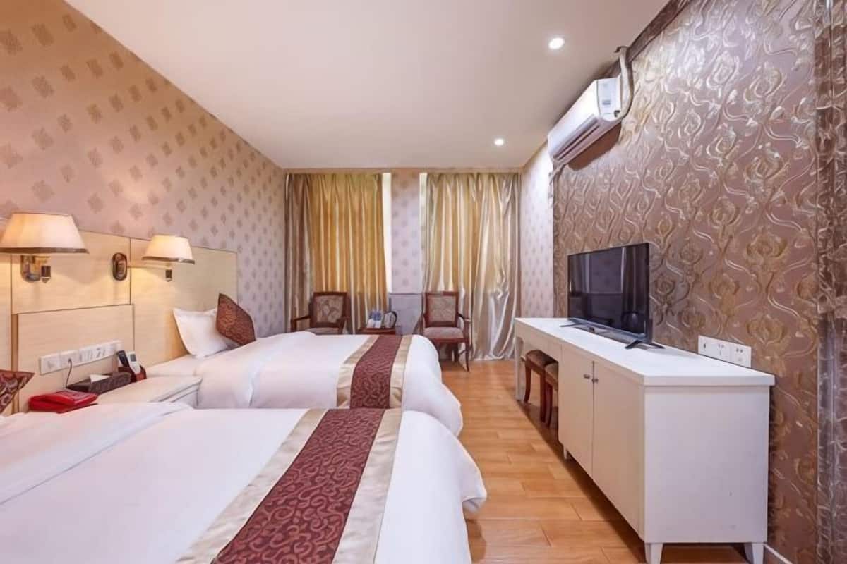 Ein Hotelzimmer mit zwei Betten, einem Fernseher, einem Schreibtisch und einem Stuhl.