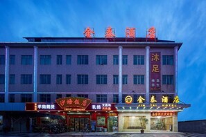 Un hotel de varios pisos con señalización para un restaurante y un hotel llamado 'Jin Tai Hotel'.
