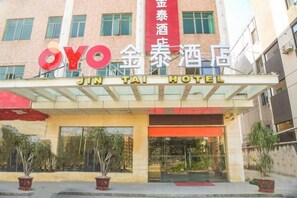 Een hotelentree met een opvallend bord voor Jin Tai Hotel en een verticaal bord met de naam Jin Tai Hotel.