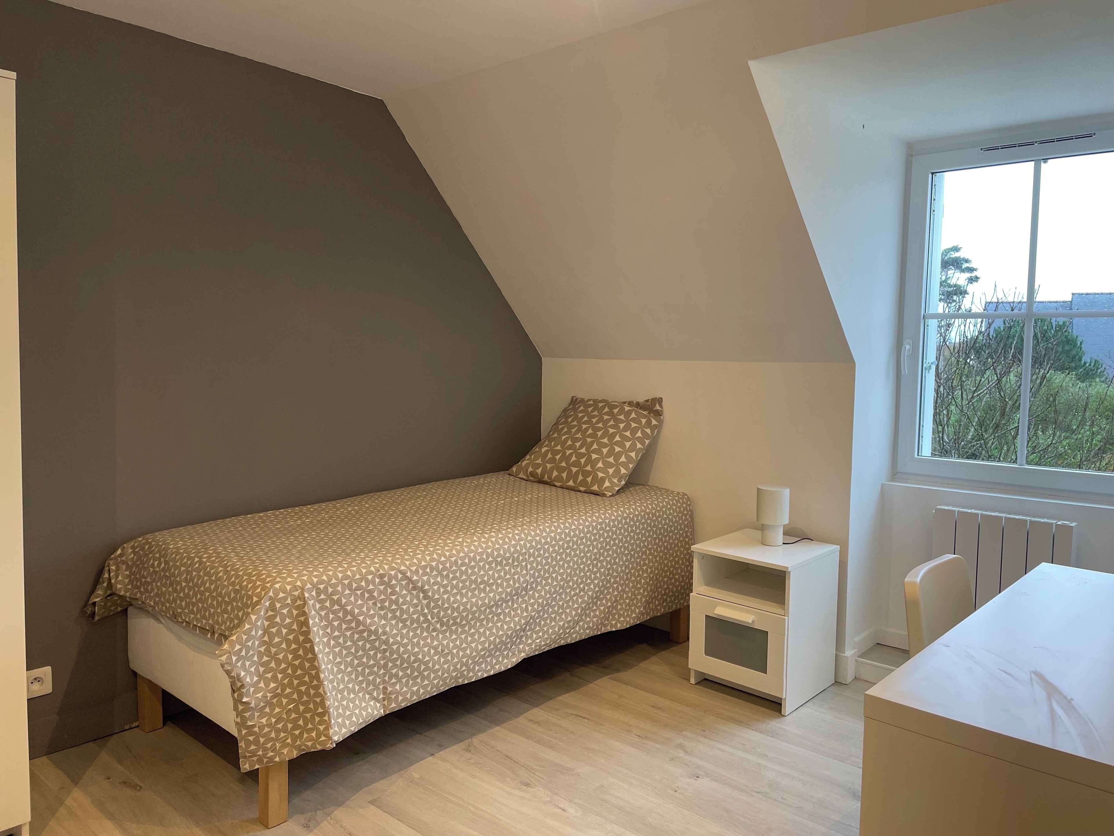 Une chambre à coucher avec un lit, une table de chevet et une fenêtre.