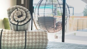 A bed with rolled towels and a hanging chair by a window with a view.