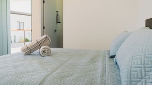 A bedroom with a bed, a rolled-up towel, and a door leading to a balcony.