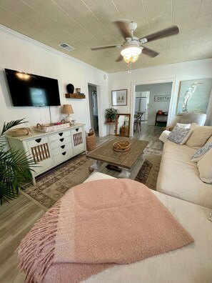 A living room with a television, a ceiling fan, a coffee table, and a couch. - High Tide, A Coastal Cottage (Port St. Joe)